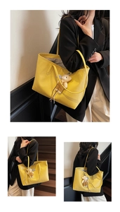 Close-up of bright yellow tote bag with pebble leather texture and a cute bear charm
