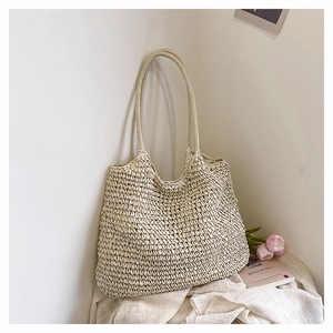 Detail of hand-woven straw tote bag with delicate texture and slim shoulder straps