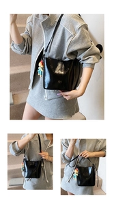 Detail view of a black glossy bucket bag with a colorful cartoon charm on a shoulder strap