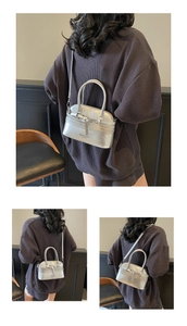 Detail view of the silver metallic mini shell bag with handles and crossbody strap