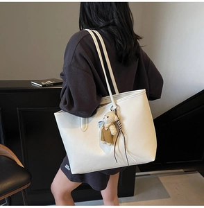Detail of white large tote bag with cute plush bear charm and pebbled leather texture
