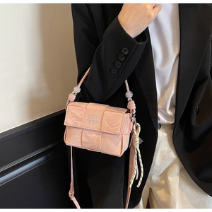 Detail of pink woven crossbody bag with metallic logo, beaded strap, and pleated texture