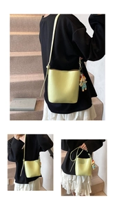 Detail view of lime green bucket bag with pearl strap and cute cartoon doll pendant