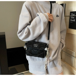 Detail of black woven square bag with white letter print on grey waffle set worn by model