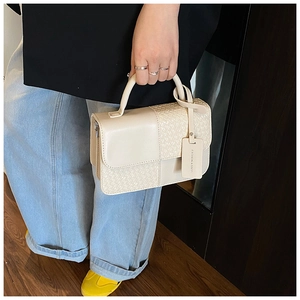 Détail du sac à main crème avec motif damier tressé et étiquette de mode chic