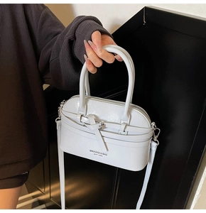 Detail of light gray shell handbag featuring elegant buckle strap and logo print