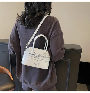 White shell-shaped leather crossbody bag worn by a model showing style and scale