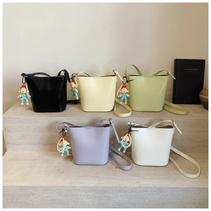 Collection of minimalist leather bucket bags in pastel colors on stone steps with charms