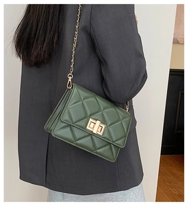 Sac bandoulière matelassé vert foncé avec fermoir doré porté par un mannequin