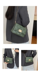 Détail d'un sac bandoulière vert matelassé avec chaîne dorée et fermoir rotatif