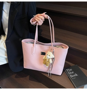 Pink lychee grain leather tote bag with a plush bear charm and metallic detail