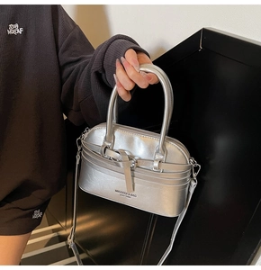 Detail of silver shell bag with metallic texture and branded front buckle strap