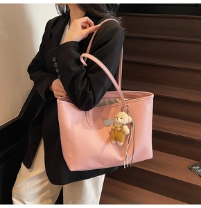 Pink lychee texture tote bag with a cute bear charm shown on a shoulder