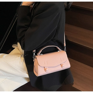 Dettaglio della borsa rosa in pelle martellata con bottoni in resina e fibbie in metallo