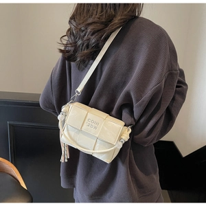 Detail view of woven cream crossbody bag with COIH 2DN embossing and fringe tassel