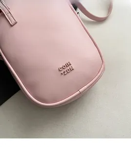 Dettaglio ravvicinato della borsa porta cellulare in ecopelle rosa con logo in metallo lucido