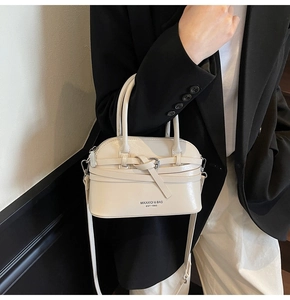 Detail of a beige shell-shaped handbag with knot decoration and silver buckle for women