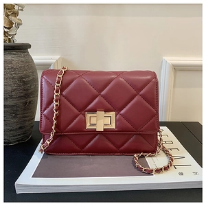 Détail du sac à bandoulière matelassé bordeaux avec fermoir en métal doré sur magazine
