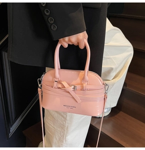 Close-up of pink shell-shaped leather handbag with crossbody strap and metallic buckle
