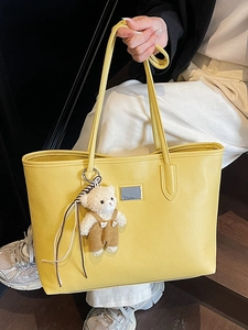 Bright yellow pebbled leather tote bag with a silver logo plate and cute bear charm