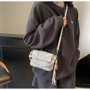 Detail of a beige woven crossbody bag featuring a COIH 2DN embossed logo and texture