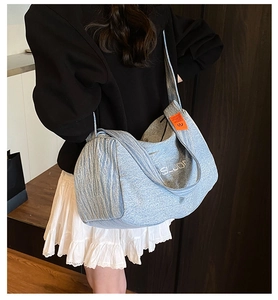 Dettaglio della borsa tote in denim azzurro con ricamo bianco ed etichetta arancione
