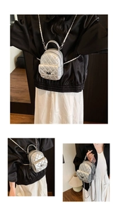 Detail eines silbernen gesteppten Minirucksacks mit Metallic-Finish und Metallketten