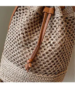 Detailed close-up of hollow woven texture and brown leather drawstring on bucket bag