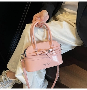 Detail of pink patent leather shell bag with knot decor and MIKAXIQI logo print