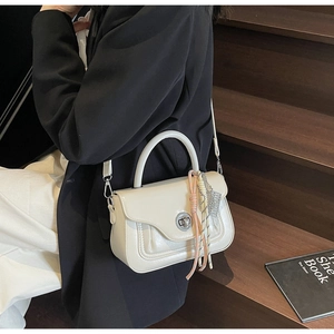 Detail of a creamy white glossy leather crossbody bag featuring a silver twist-lock closure
