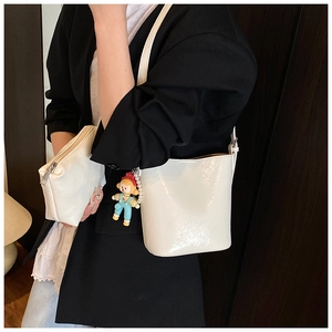 Close-up of a white glossy bucket bag set featuring a mini pouch and colorful charm