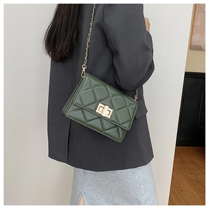 Détail du sac bandoulière vert foncé avec fermoir doré tournant et chaîne en métal tressé
