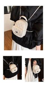 Detail eines weißen Mini-Rucksacks aus gestepptem Lackleder mit Metallkette und Drehverschluss