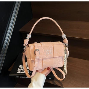 Detail of pink woven leather handbag featuring clear bead handle and fringe charm