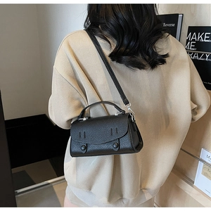 Vista posteriore di una modella con la borsa a tracolla nera in pelle martellata e tracolla