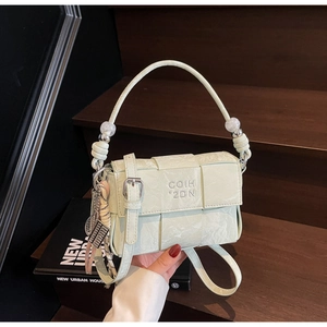 Detail of light green woven handbag featuring silver logo and beaded handle accents