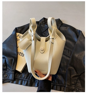 Close-up of litchi pattern texture and metal buckle on creamy white bucket bag
