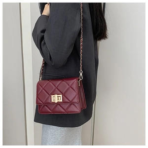 Détail d'un sac à main en cuir matelassé bordeaux avec bandoulière chaîne dorée