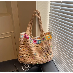 Close-up of beige crochet tote bag with colorful sunflower embroidery and pearl accents