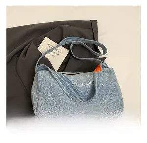 Dettaglio della borsa tote in denim azzurro con ricamo SOLJO bianco ed etichetta arancione