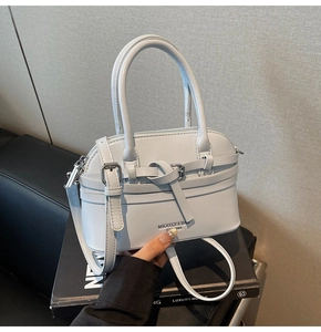Close-up of a light blue shell-shaped handbag with top handle and knotted buckle detail