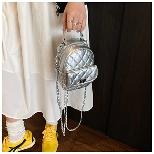Detail eines silbernen gesteppten Mini-Rucksacks mit glänzendem Metallic-Finish und Kette