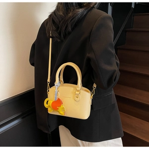 Detail of creamy yellow leather bucket bag with gold lettering and colorful elephant charm