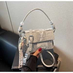 Detail of woven flap crossbody bag with decorative silver beads and metal abacus charm