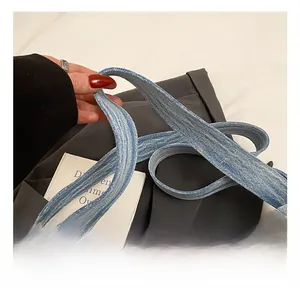 Dettaglio macro della tracolla in denim blu della borsa tote con stampa di lettere bianche