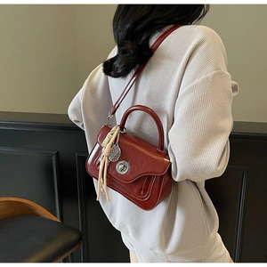 Deep red patent leather crossbody bag with silver clasp and tennis racket charm