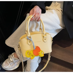 Detailed macro view of the cream leather bucket bag texture and elephant charm