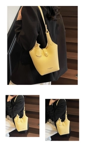 Detail view of yellow litchi pattern leather bucket bag with brand logo and strap