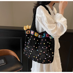 Detail of sunflower embroidery and colorful beads on a black crochet knit tote bag