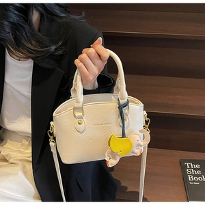 Detail of cream white pebbled leather bucket bag with a cute yellow elephant charm